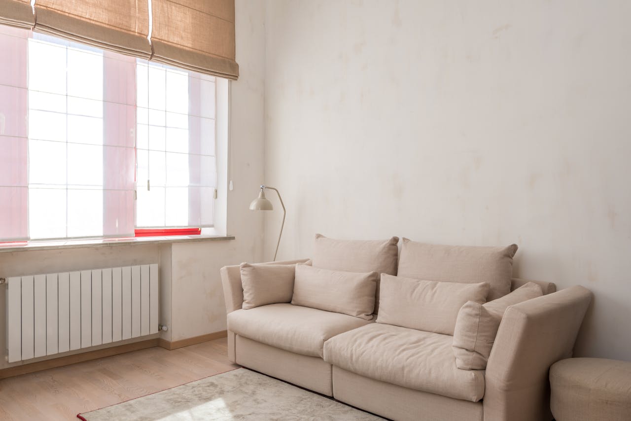 Bright and airy minimalist living room featuring a beige couch and natural light.